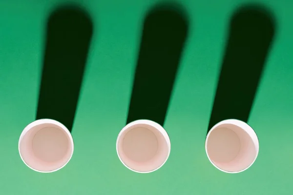 Vista dall'alto della tazza di carta rossa in fila su sfondo verde con ombre — Foto Stock
