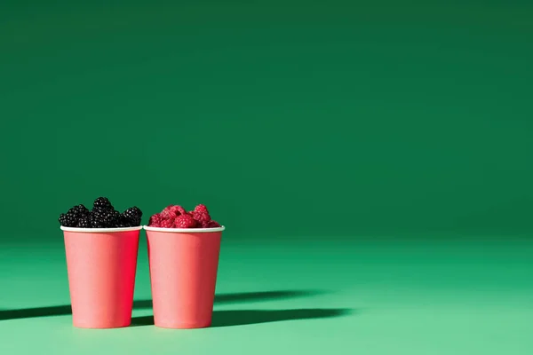 Frische Beeren in roter Tasse auf grünem Hintergrund. mit Kopierraum — Stockfoto