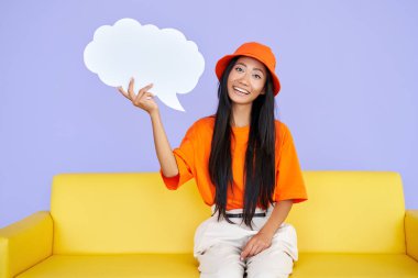 Güzel hippi kız elinde boş bir konuşma balonuyla kanepede oturuyor.