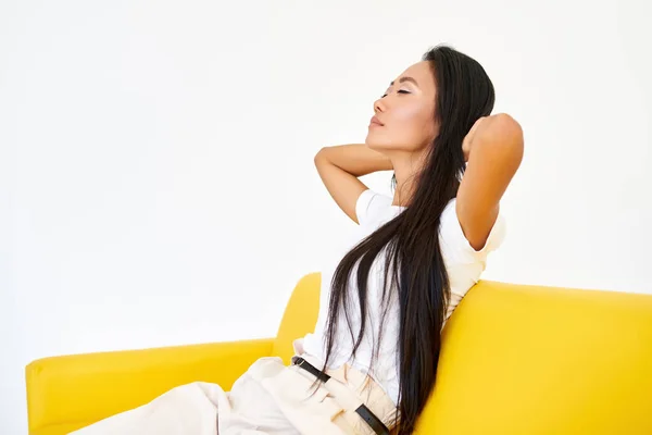 Young pretty woman closed her eyes sitting on yellow sofa and relaxing after busy day — Stock Photo, Image