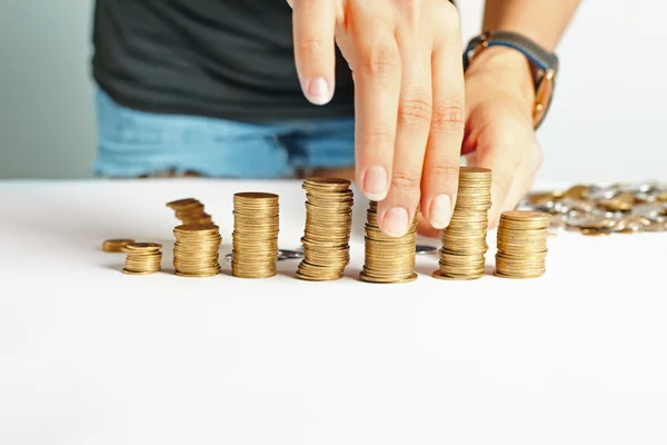 Girl put coins to stack of coins — Stockfoto