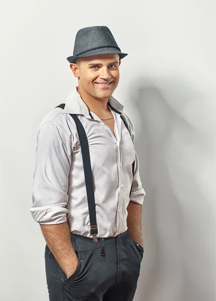 Hombre guapo sonriente con sombrero y tirantes — Foto de Stock