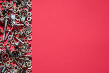 Karışık vida somun ve cıvatalar kırmızı arkaplan üzerinde büyük kopya alanı ile sınır oluşturma