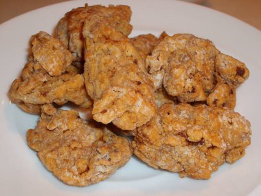 Orta pişmiş kızarmış tavuk ısırıkları, beyaz bir tabakta.