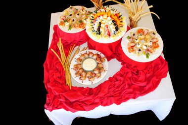 Tabaklardaki farklı aperatifler kalp şeklinde masa örtüsü, koyu arka plan.
