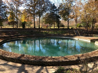 Arkansas sularına yansıyan renkli ağaçlarla dolu yuvarlak doğal havuz..