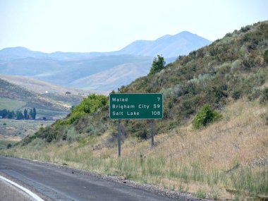 Utah 'taki yol kenarı tabelasında Malad, Brigham City ve Salt Lake City' ye gidiş yönleri yazıyor..