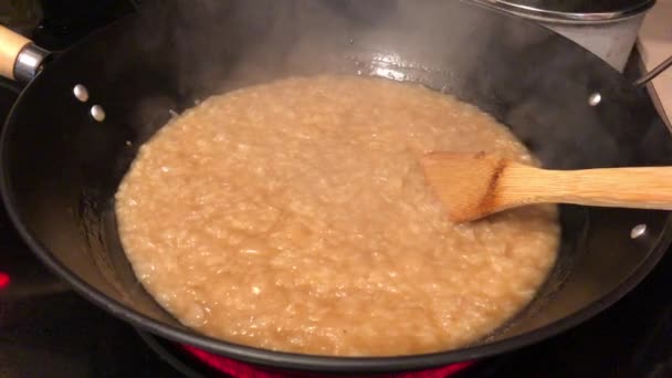 Hand-held shot van een kokende pan kleverige rijst met kokosmelk op een kookplaat — Stockvideo
