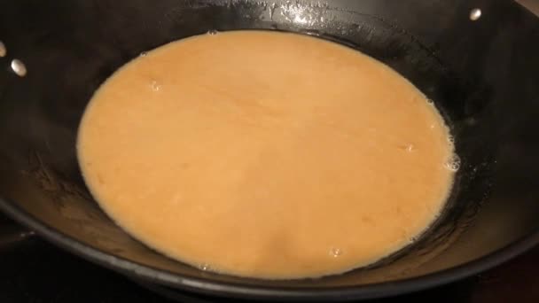 Met de hand vast te houden shot van gekarameliseerde suiker en kokosmelk kokend in een pan — Stockvideo