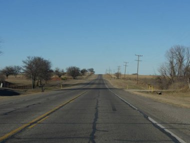 Kışın yol kenarlarında yapraksız ağaçlar olan düz bir yol..