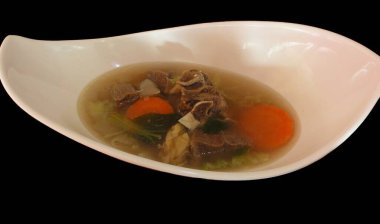 Orta boy sığır pirzolası çorbası, havuç, lahana ve siyah arka plan.