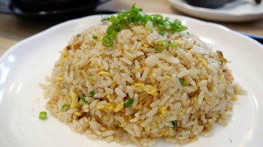 Dilimlenmiş yeşil soğanlı büyük bir kepçe kızarmış pirinç.