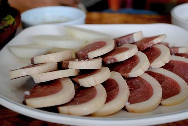 Restoran barbekü istasyonunda ızgaraya hazır beyaz bir tabakta sığır eti dilimleri..