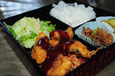 Ekmekli tavuk, spagetti, pilav ve sebzeli bir bento paketini kapat..