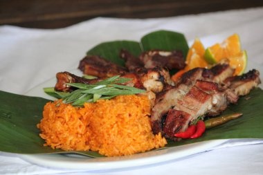 Geleneksel Chamorro mutfağı. Kırmızı pilav ve ızgara et. Muz yaprağında servis ediliyor.