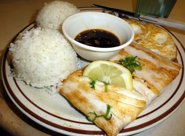 Izgara mahmahi balığı dilimleri, iki kepçe pilav ve çırpılmış yumurta, ve soya sosu..