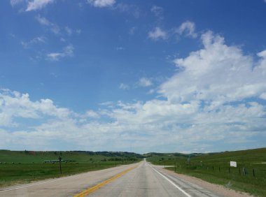 Gökyüzünde pamuklu bulutlar olan Wyoming manzarası.