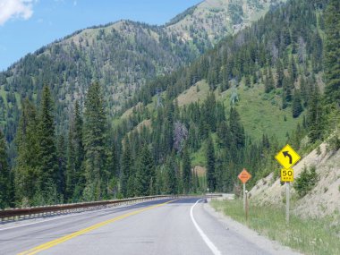 Scenic landscape with road warning signs at Yellowstone National Park, Wyoming. clipart