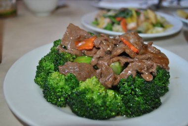 Masada sığır eti ve brokoli olan beyaz tabak. 