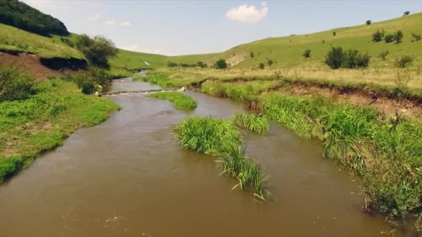 Stunning luchtfoto van weelderige groene heuvels met een kleine rivier die door hen — Stockvideo