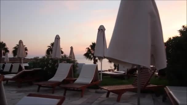 Ligstoelen en parasols bij het zwembad, dicht bij het strand — Stockvideo