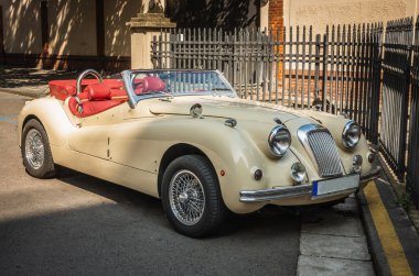 Caddede kırmızı döşemeleri olan eski parlak bir araba.