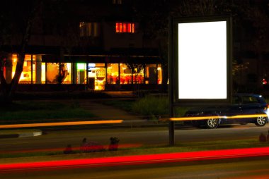 Gece şehrinin arka planında boş tabela var. Tasarım için maket. Reklam için boş yer. Çerçevenin kenarındaki pankarttaki keskinlik.