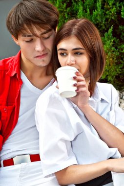 Erkek ve kadın birlikte dışarıda öğle yemeği yiyorlar. Patates yiyen bir çift. Fast food ve sokak yemeği kavramı. Kağıt kaplarda yemek ve tek kullanımlık bardaklar..