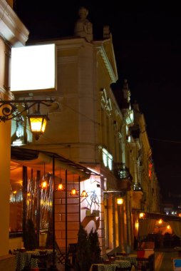Gece şehrinin arka planında boş tabela var. Tasarım için maket. Reklam için boş yer. Çerçevenin kenarındaki pankarttaki keskinlik.