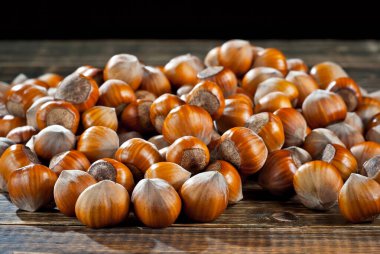 Fındıklar üst üste yığılmış. Eski ahşap bir tahtanın üzerindeki fındık dokusu. Kahverengi eski bir masada bir sürü fındık.