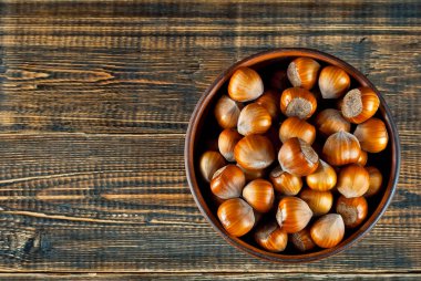 Kahverengi ahşap arka planda bir kasede fındık. Eski püskü bir tahtada bir sürü fındık var. Yemek yakınında metin ve kopyalama alanı.