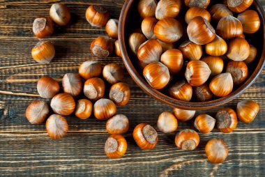 Kahverengi ahşap arka planda bir kasede fındık. Eski püskü bir tahtanın üzerinde bir sürü fındık.