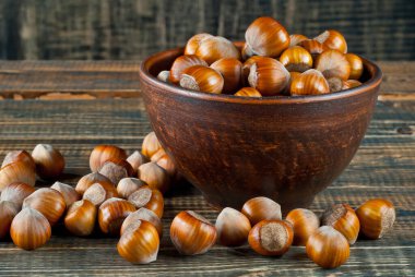 Kahverengi ahşap arka planda bir kasede fındık. Eski püskü bir tahtanın üzerinde bir sürü fındık.