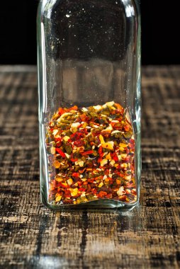 Cam kavanozdaki çeşitli baharatların karışımı. Siyah, eski püskü bir tahtada baharatlar ve baharatlar. Baharat yakınındaki metin için boş alan ve kopyalama alanı.