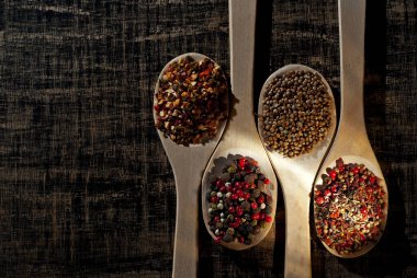 Tahta kaşıkta çeşitli baharatların karışımı. Eski püskü bir tahtada baharatlar ve baharatlar. Mesaj ve fotokopi için kaşığa yakın bir yer. Sanatsal bir efekt olarak dramatik ışık karşıtlığı.