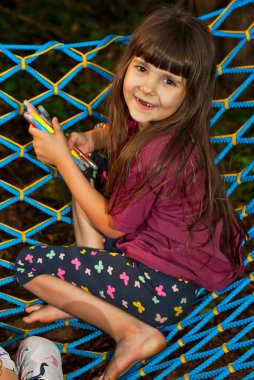 Çocuklar hamakta oturur. Kızlar yazın doğada oynarlar. Bahçede çocuk eğlencesi..