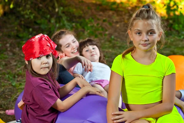 Children rest in nature. Boys and girls play on an inflatable sofa. Summer vacation in the garden.