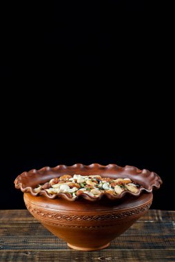 Pek çok çatlak türü kapanır. Tahtadaki farklı fındıkların dokusu. Kahverengi bir masada kil kase..