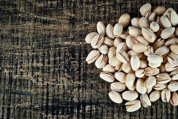 Pistachio dokusunu yakından çek. Siyah tahta üzerinde fındıklar. Sanatsal bir efekt olarak dramatik bir ışık. Fındık yakınındaki metin için boşluk ve boş alanı kopyala.