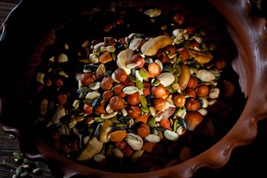 Pek çok çatlak türü kapanır. Tahtadaki farklı fındıkların dokusu. Kahverengi bir masada kil kase. Sanatsal bir efekt olarak dramatik ışık karşıtlığı.