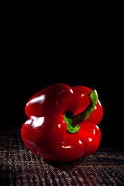 Siyah tahta üzerinde kırmızı dolma biber. Sanatsal bir efekt olarak dramatik bir ışık. Biber yakınındaki metin için boşluk ve boş alanı kopyala.