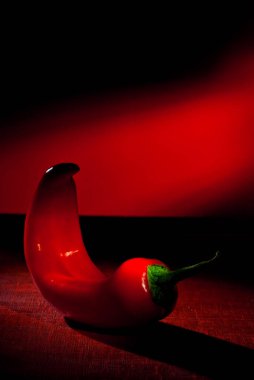 Acı biberler kapanıyor. Tahtadaki Şili biberi. Kırmızı arka planda sebzeler. Sanatsal bir efekt olarak dramatik ışık karşıtlığı.