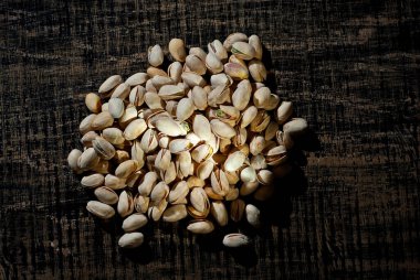 Pistachio dokusunu yakından çek. Siyah tahta üzerinde fındıklar. Sanatsal bir efekt olarak dramatik ışık karşıtlığı.