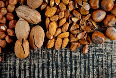 Çeşit çeşit fındık vardır. Siyah tahta üzerinde bir yığın fındık. Fındıklar masanın üzerinde duruyor..
