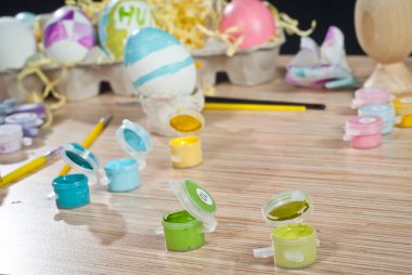 Ahşap bir masada çok renkli boyalar ve Paskalya yumurtaları. Paskalya yumurtalarını boyamak için ayarlar.