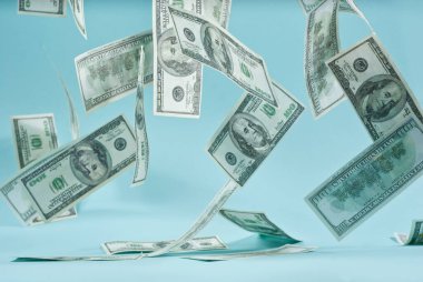 Mavi arka planda yeşil dolar banknotları. 100 dolarlık banknotlar kapanıyor. Zenginlik ve başarı kavramı. Havada para uçuşuyor..