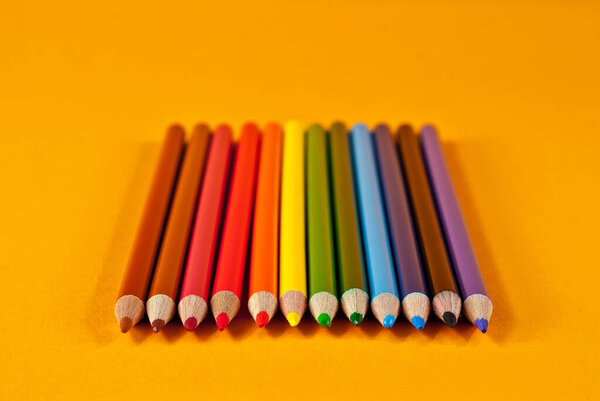 Multicolored pencils on an orange background.