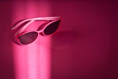 Pembe arka planda güneş gözlüğü. Kadın bardakları kapanıyor. Gözlük yakınındaki metin için boşluk ve yeri kopyala.