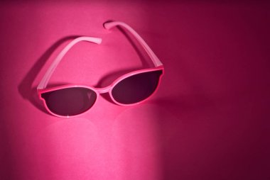 Pembe arka planda güneş gözlüğü. Kadın bardakları kapanıyor. Gözlük yakınındaki metin için boşluk ve yeri kopyala.