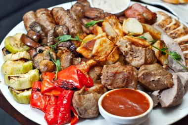 Tabakta çeşit çeşit et var. Bir yığın halinde farklı et ve patates türleri. Büyük bir tabakta soslu aperatif..